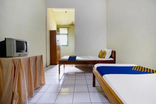 a room with two beds and a tv in it at Hotel O Wisma Lec Syariah in Garut