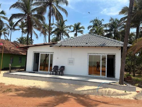 a small white building with palm trees in the background at White Waves Beach Front Villa in Kaup