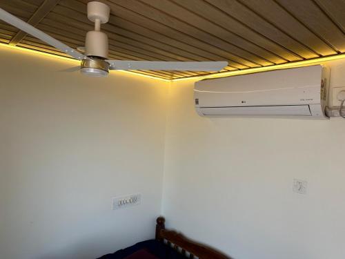 a ceiling fan in a room with a white wall at White Waves Beach Front Villa in Kaup