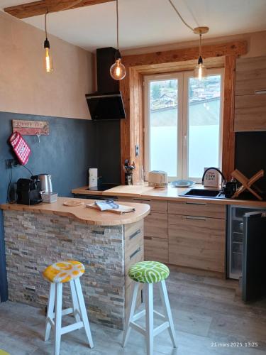 une cuisine avec un comptoir et deux tabourets dans l'établissement Appartement Le Bihé La Bresse, à La Bresse
