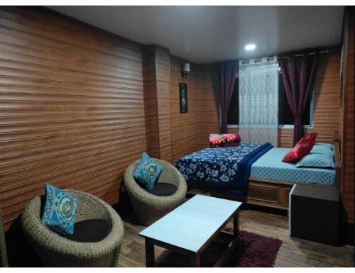 a bedroom with a bed and chairs and a table at Moormi homestay, Darjeeling in Jālāpahār