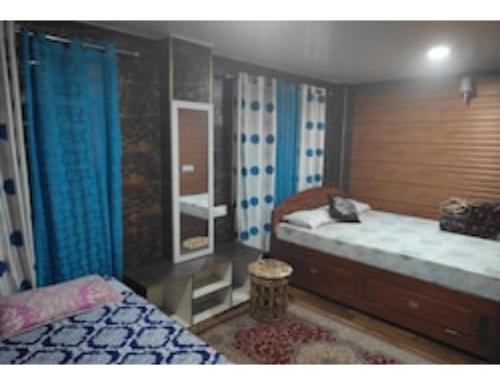 a bedroom with two beds and blue curtains at Moormi homestay, Darjeeling in Jālāpahār