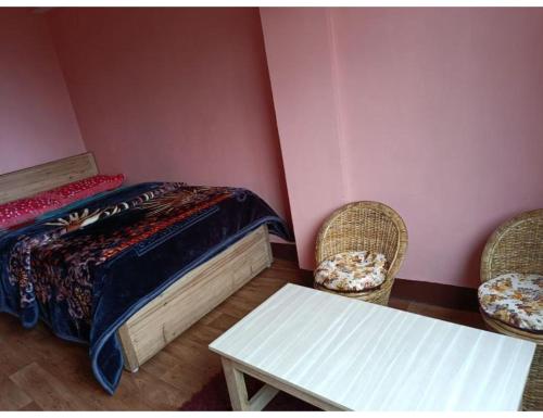 a bedroom with a bed and two chairs and a table at Moormi homestay, Darjeeling in Jālāpahār