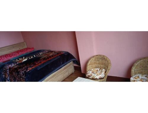 a bedroom with a bed and two chairs and a table at Moormi homestay, Darjeeling in Jālāpahār