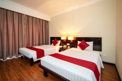a hotel room with two beds with red pillows at Khemara Angkor Hotel & Spa in Siem Reap