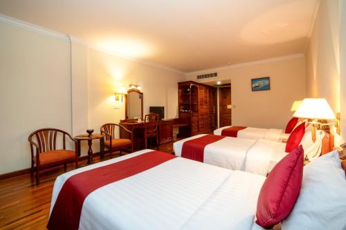 a hotel room with two beds and a desk at Khemara Angkor Hotel & Spa in Siem Reap