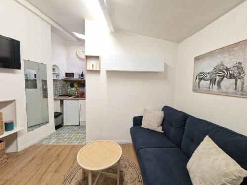 een woonkamer met een blauwe bank en een tafel bij Le Massillon #Hypercentre in Clermont-Ferrand