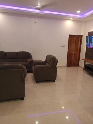 a living room with couches and a flat screen tv at Blue Dolphin homestay in Tadri