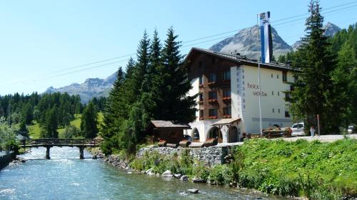 a bridge over a river next to a building at Hotel Nolda in St. Moritz