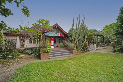 a house with a red sign in front of a yard at Hotel O Griya Estu Wening in Sleman