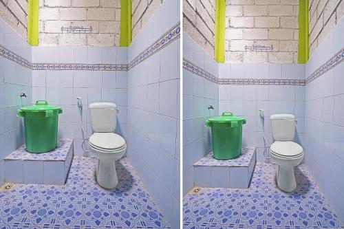 a bathroom with two toilets and a green trash can at Hotel O Griya Estu Wening in Sleman
