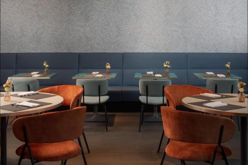 a dining room with tables and chairs and a blue wall at NH Savona Darsena in Savona