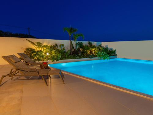 a swimming pool with two chairs next to a wall at ResortVilla-KAPUKA in Kouri