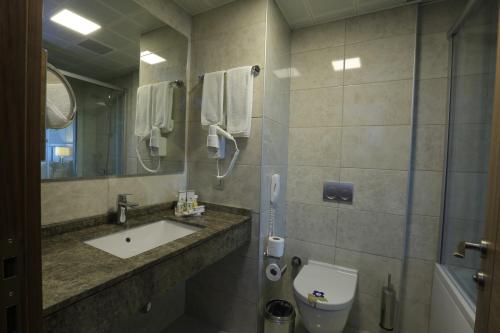 a bathroom with a sink and a toilet and a mirror at Best Western Premier Karsiyaka Convention & Spa Hotel in Izmir