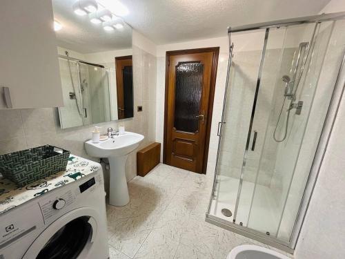 a bathroom with a shower and a sink and a washing machine at La casa nel borghetto in La Salle