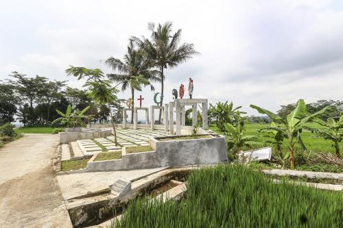 un monumento in un campo con palme sullo sfondo di OYO Homes 91151 Desa Wisata Kreatif Perdamaian Srumbung Gunung a Karangjati