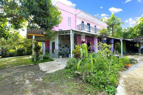 a pink house with a garden in front of it at OYO Homes 91154 Desa Wisata Wayang Manyaran Wonogiri in Wonogiri