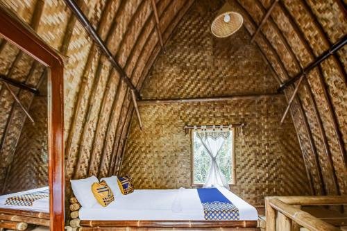 a room with two beds in a bamboo house at Hotel O Desa Wisata Bangunharja in Banjar