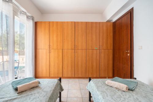 a bedroom with two beds and a wooden cabinet at Villa May Rose in Kalathos