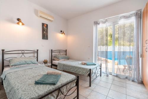 two beds in a room with a view of a pool at Villa May Rose in Kalathos