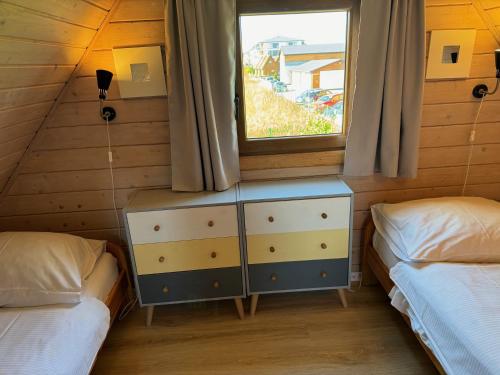 ein Schlafzimmer mit zwei Einzelbetten und einem Fenster in der Unterkunft Koralia Domki i Apartamenty Basen z podgrzewaną wodą in Sarbinowo