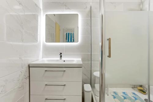 une salle de bain blanche avec un lavabo et un miroir dans l'établissement Centre ville, parking, 2 min gare, à Saint-Raphaël