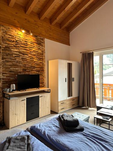a bedroom with a bed and a television and a brick wall at Touristenheim Bergfreude in Leukerbad