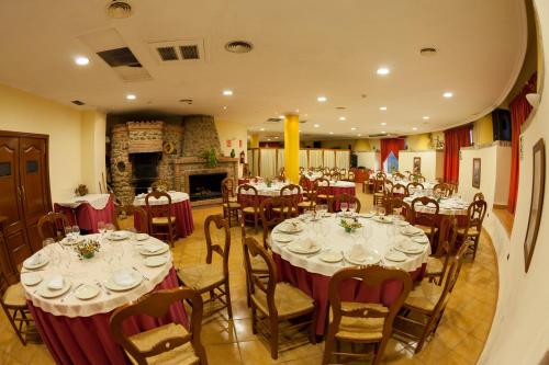 Hotel Paraje La Lambra في روس: غرفة طعام مع طاولات وكراسي ومدفأة