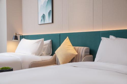 two beds in a hotel room with white sheets at Hilton Garden Inn Zhangjiajie Wulingyuan in Zhangjiajie