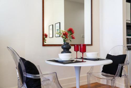a table with chairs and a vase with flowers on it at Kiwiana Suite - Auckland CBD - rooftop pool in Auckland