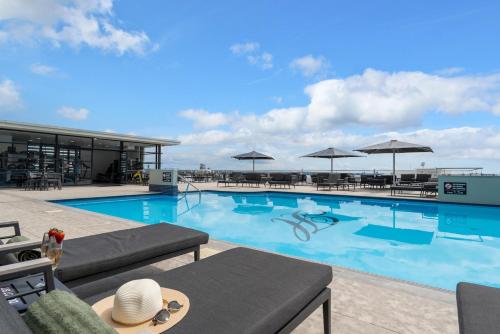 a large swimming pool with chairs and umbrellas at Kiwiana Suite - Auckland CBD - rooftop pool in Auckland