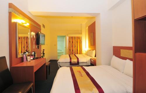 a hotel room with two beds and a television at Nice Hotel in Kaohsiung