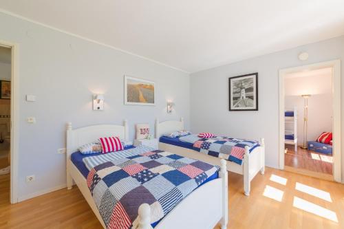 two beds in a bedroom with white walls and wood floors at Ferienhaus Krause in Trent