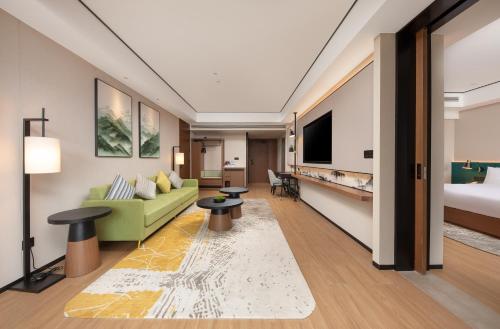 a hotel room with a green couch and a bed at Hilton Garden Inn Zhangjiajie Wulingyuan in Zhangjiajie