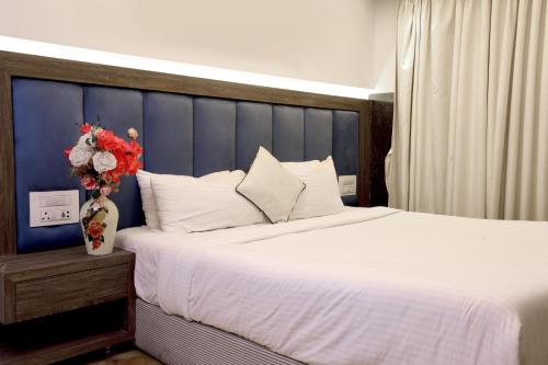 a bedroom with a large bed and a vase with flowers at Kumar Resort By Turtle, Lonavala in Lonavala