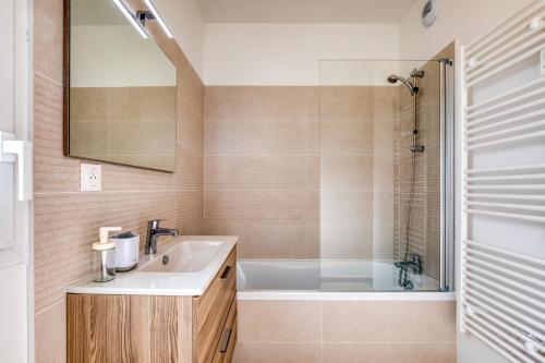 une salle de bain avec un lavabo et une baignoire dans l'établissement Appartement Grains de Sable, à Le Castellas