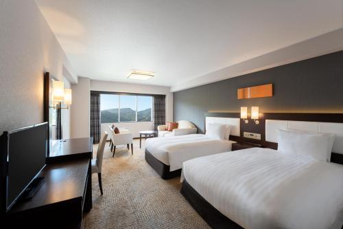 a hotel room with two beds and a television at Grand Mercure Beppu Bay Resort & Spa in Beppu