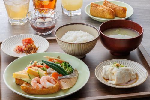 a table with plates of food and bowls of rice at Via Inn Shinsaibashi in Osaka