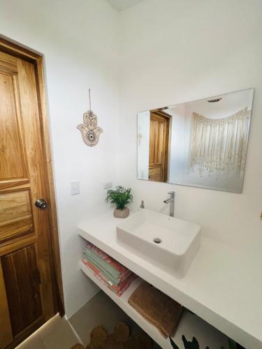 a white bathroom with a sink and a mirror at Casa Ophelia in Tamarindo