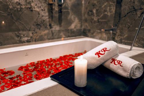 a candle and towels in a bath tub with red flowers at Kumar Resort By Turtle, Lonavala in Lonavala
