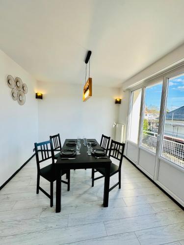 une salle à manger avec une table et des chaises et une grande fenêtre dans l'établissement Appartement spacieux à Caen, à Caen