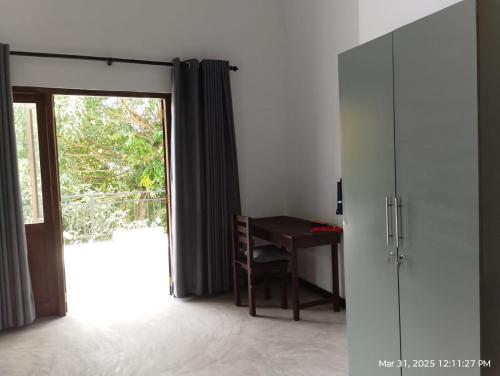 a room with a desk and a sliding door with a window at The Nest in Weligama