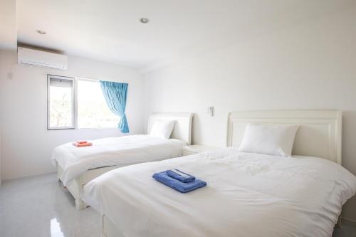 two beds with a blue towel on them in a room at Shallows in Onna
