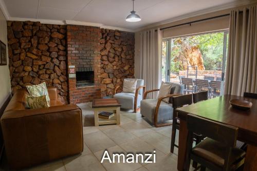 a living room with a fireplace and a table and chairs at Thabela Thabeng in Parys