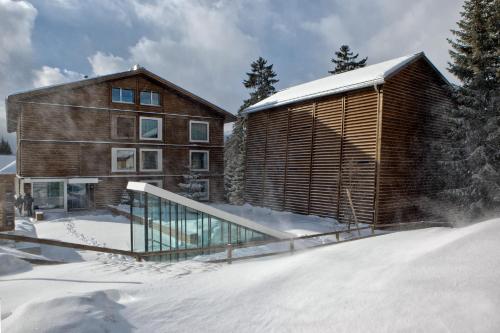a wooden house in the snow next to a building at Valbella Resort in Lenzerheide