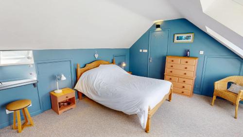 Saddle Cottage في بينزانس: غرفة نوم بجدران زرقاء وسرير وكرسي