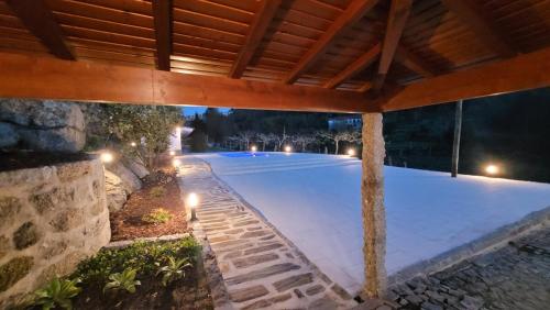 an outdoor swimming pool at night with a wooden roof at Casa Dos Strecht's in Castelo de Paiva