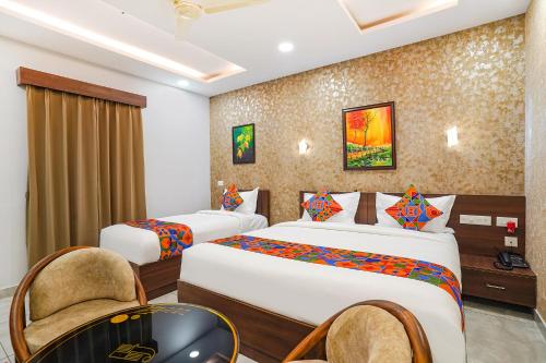a hotel room with two beds and a chair at Oriva Freshco in Bengaluru