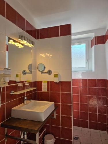 a bathroom with a white sink and red tiles at Brit Hotel des Halles in Concarneau