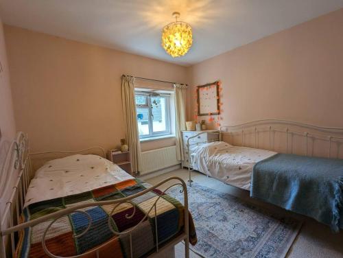 a bedroom with two beds and a chandelier at Cottage in the Heart of Frome in Frome